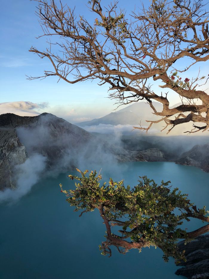 Services Breathtaking view of Ijen Crater Lake at sunrise with mist and mountains in East Java, Indonesia.