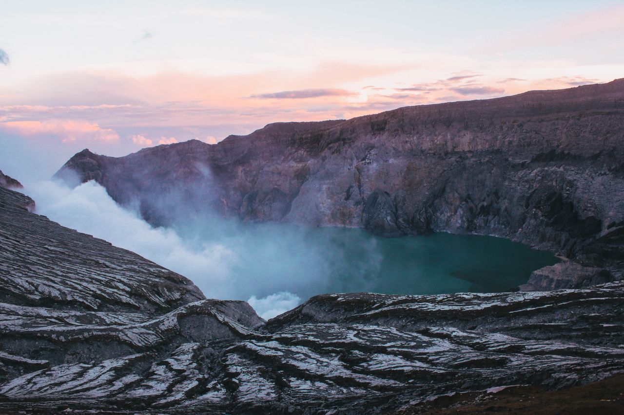 About Breathtaking view of Ijen Crater in Jawa Timur, Indonesia, showcasing sulfur clouds and expansive crater lake at sunrise.