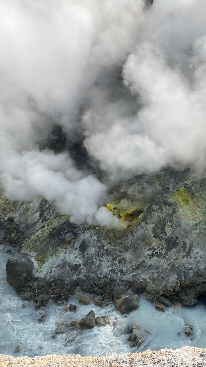 Rough stony volcanic terrain with emitting sulfur vapor in high mountains in daytime